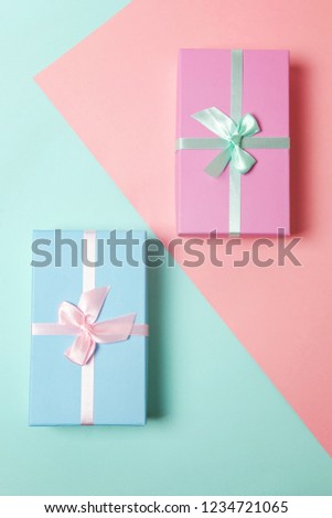 Small gift box wrapped pink and blue paper isolated on blue and pink pastel colorful trendy geometric background. Christmas New Year birthday valentine celebration present romantic concept