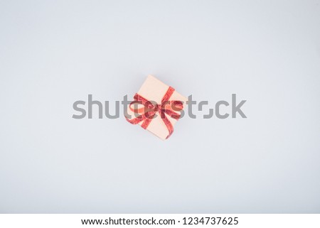 Craft box with red ribbon bow. Valentine day concept. Trendy minimalistic flat lay design background. Light cold toning. Horizontal