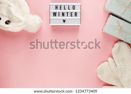 Warm, cozy winter clothing, lightbox and christmas decorations  as frame on pink background. Christmas concept flat lay. hello winter title