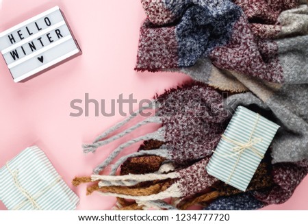 Warm, cozy winter clothing, scarf, lightbox and christmas decorations  as frame on pastel  pink background. Christmas concept flat lay. hello winter title  