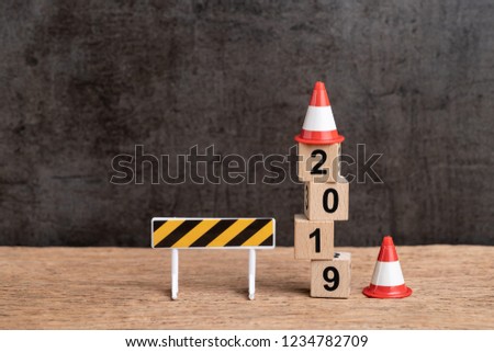 Year 2019 new year changing concept, under construction sign and traffic cone on cube wooden block building number 2019 on wood table with dark blackboard background with copy space.