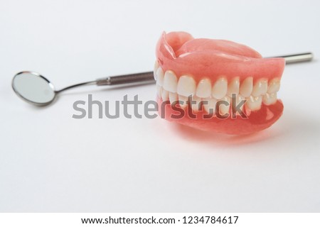 Artificial teeth on a white background with copy space. Dentist appointment, dentistry instruments and dental hygienist checkup concept with teeth model dentures and mouth mirror Royalty-Free Stock Photo #1234784617