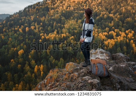 Walking young girl in style of boho and hat on background of autumn mountains