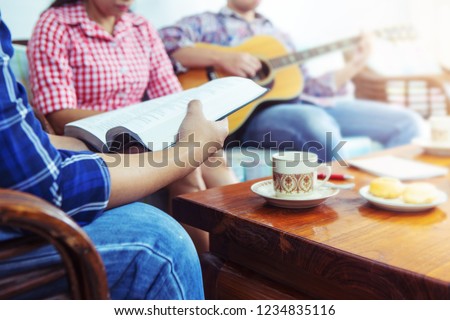 A young  holding bible while his friend plays guitar at home, Christian family, small group or house church worship concept Royalty-Free Stock Photo #1234835116
