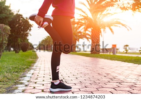Young, fitness woman in sneakers and sportswear does stretching muscles before sports training and jogging. Sports and healthy lifestyle. Sport and fitness legs  