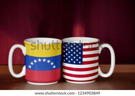 USA and Venezuela flag on two cups with blurry background