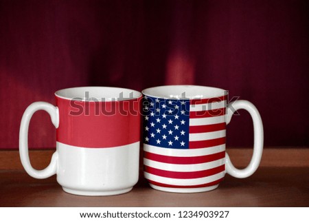 USA and Indonesia flag on two cups with blurry background