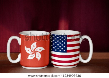 USA and Hong Kong flag on two cups with blurry background