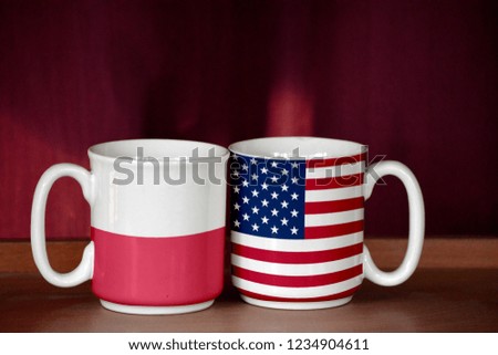 USA and Poland flag on two cups with blurry background