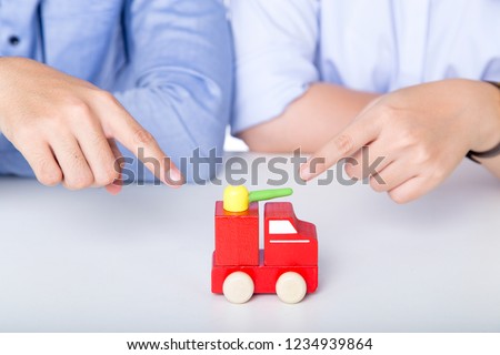 
Hand pointing to the red toy car
