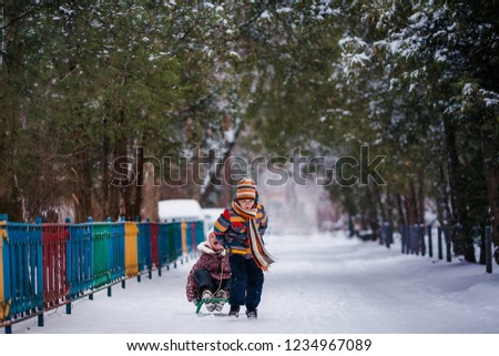 Boy and girl sledding in the snowy yard. Winter background.