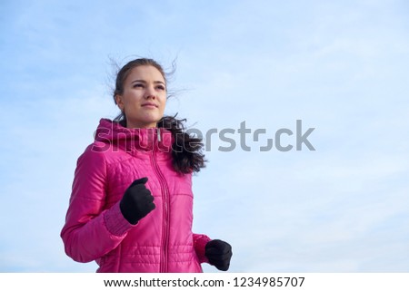 Running athlete woman sprinting during winter training outside in cold snow weather. Close up showing speed and movement.