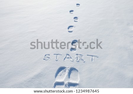 Concept picture.inscription start and footprints in the snow