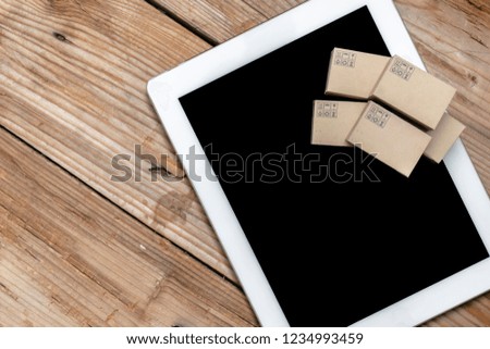 Online shopping,E-commerce and delivery service concept.Paper box stacked on the tablet.Paper Box with Safe Transportation Symbols, depicts customers order things from retailer sites via the internet.
