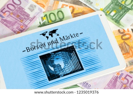 Euro banknotes and a Tablet PC with an online newspaper with the German title stock exchanges and markets