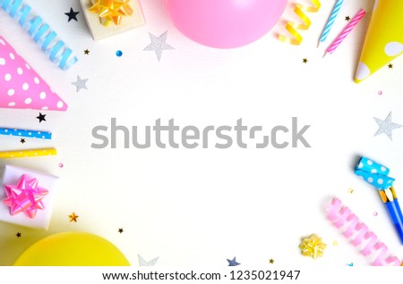 Holiday frame or background with colorful balloon, gift, confetti, silver star, carnival cap and streamer. Birthday or party greeting card. Flat lay, top view, copy space.