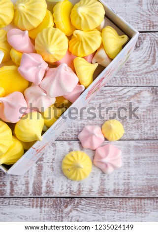 Multi-colored meringue in a gift box on wooden vintage background.