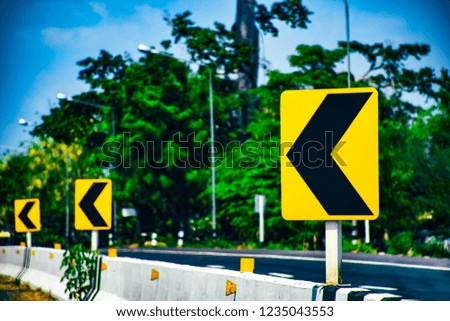 Traffic sign in bending on road to warning avoid accident, Reflected board of traffic on way, green tree beside road, Travel to countryside on holiday, Close up board of sign to cautious curve road