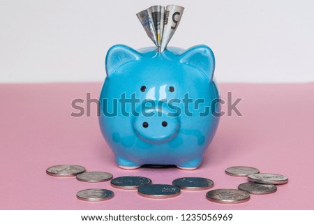 Blue piggy bank and coins on pink background.  Finance Savings concept. selective focus