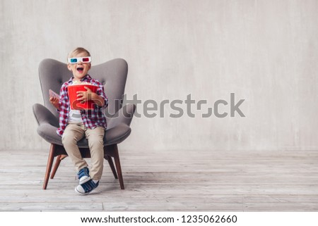 Surprised boy in 3d glasses with popcorn in cinema