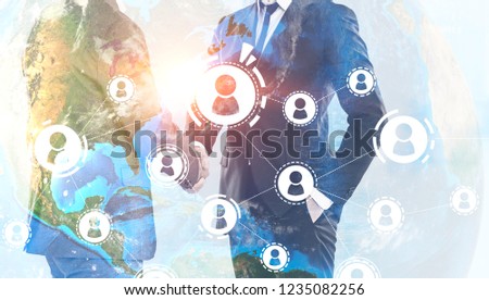 Unrecognizable businessmen shaking hands over Earth background with people network hologram. Toned image double exposure Elements of this image furnished by NASA