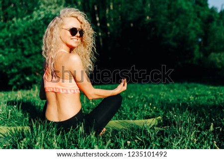 Photo of young curly woman in sunglasses lying on rug in park