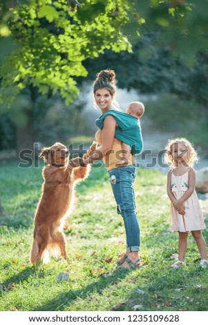 Mother with baby in sling, daughter and dog outdoor