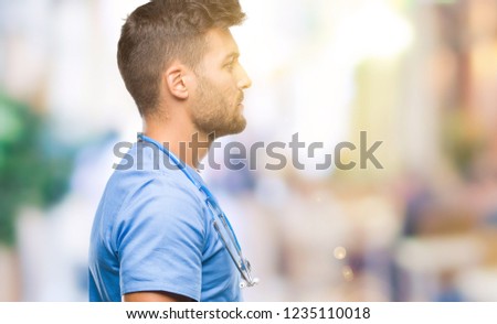 Young handsome doctor surgeon man over isolated background looking to side, relax profile pose with natural face with confident smile.