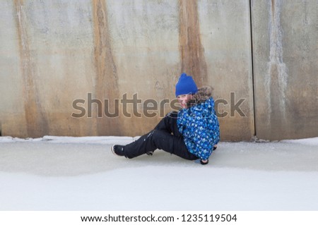 little boy in winter clothes sitting on snow
