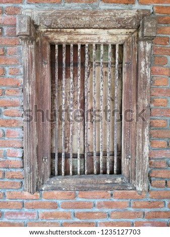 Old metal bar window with wooden frame and the red bricks wall