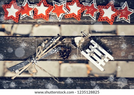 Winter outdoor composition with pine cone, decorative decorative sledge and ski and colorful felt stars on an old painted wooden bench as a background . Top view