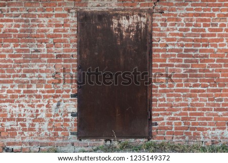 Rusty metal door in the middle of a brick wall