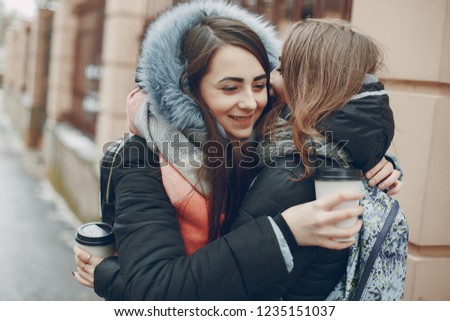 Two beautiful girl walking in the winter city with cup coffee
