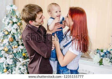 kissing baby near with Christmas tree