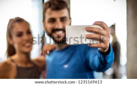 Show your healthy smile. Smiling sports couple taking self portrait in gym. Close up. Focus is on hand.