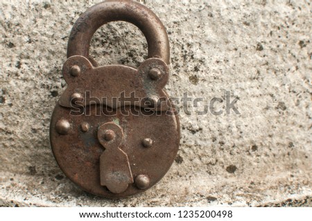 Old weathered grunge retro locked padlock closeup on solid stone surface background