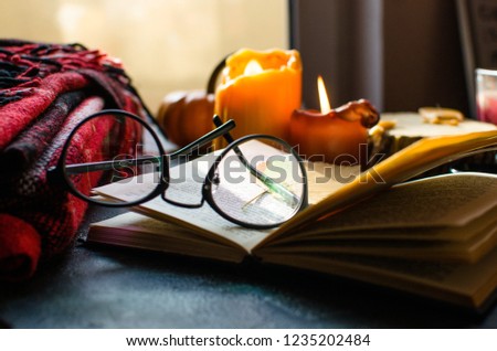 Books and candle on wooden table against dark background. Education, knowledge concept with copy space