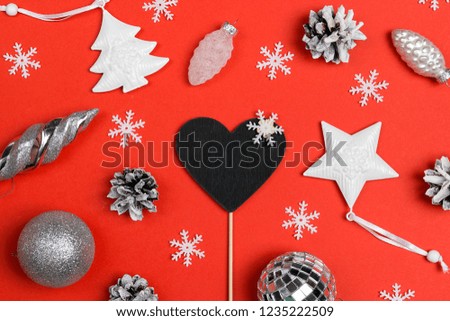 Blank blackboard-heart with white holiday decorations and cones on red background. Space for text. Top view. Christmas or New Year card.