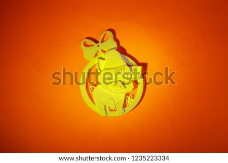 Cheerful yellow pig, in a cap with the inscription 2019, a symbol of the New Year, a toy on the Christmas tree, made of plastic on a 3D printer at home, on a red background.
