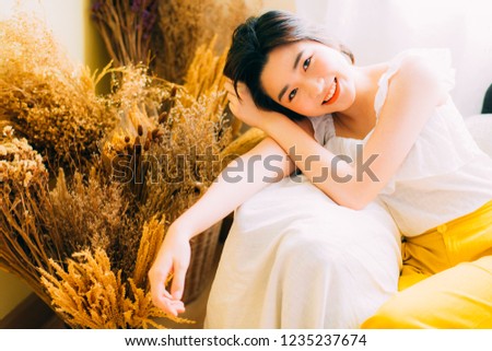 A picture of a beautiful Asian girl relaxing at home in the spring or summer. Asian girl smiles happy with bright face, glowing clear skin