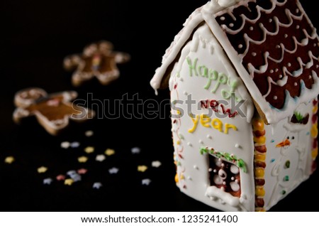 White gingerbread house with a brown roof, a window and the inscription happy New Year on a white wall