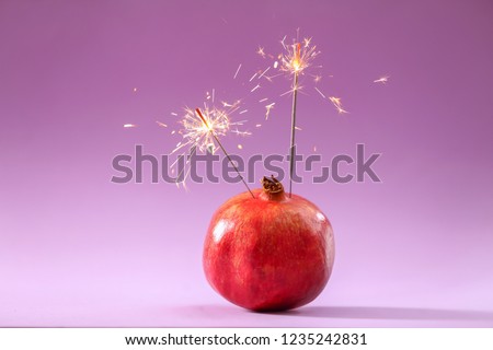 Pomegranate with festive Christmas sparklers on color background
