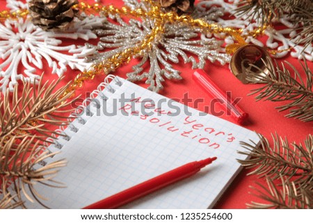 inscriptions New Year's resolution in a notebook and various New Year's decorations on a red background. New Year Christmas. holidays