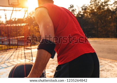 Rear view of young basketball player outdoor.
