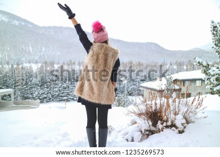 Young woman holding her hand up feeling freedom in the winter with beautiful mountain full of snow background
