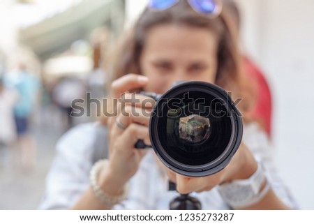 Beautiful young woman with a camera with fish eye lens in her hands, professional at work