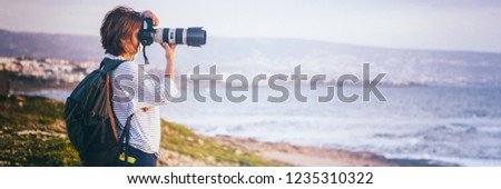 Young girl professional photographer on the beach with a camera in hand, travel and remote work, blogger