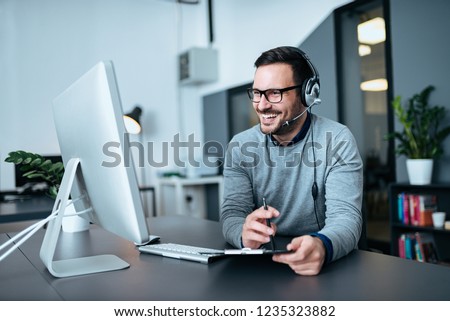 Portrait of a casual smiling businessman using headset when talking to customer. Royalty-Free Stock Photo #1235323882