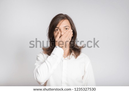 handsome business man scared and closes his mouth with his hands, long haired isolated on background