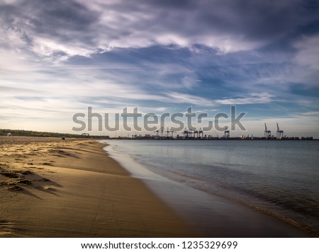 Long empty clean sand Stogi beach in Gdansk, Poland with Stalin shipyard with cranes in the background